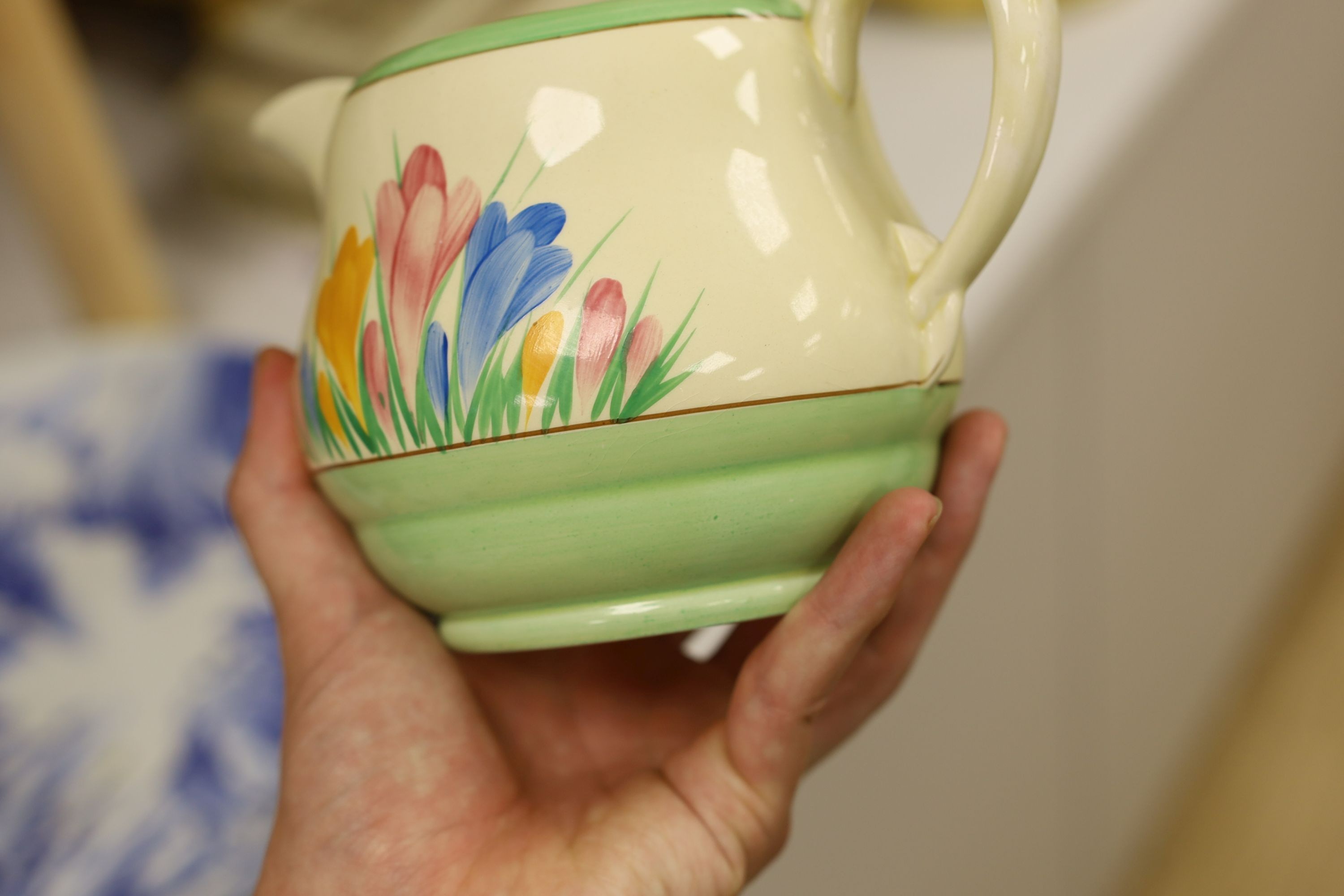 A Clarice Cliff crocus design milk jug and a Bizarre patterned side plate, jug 11.5 cms high